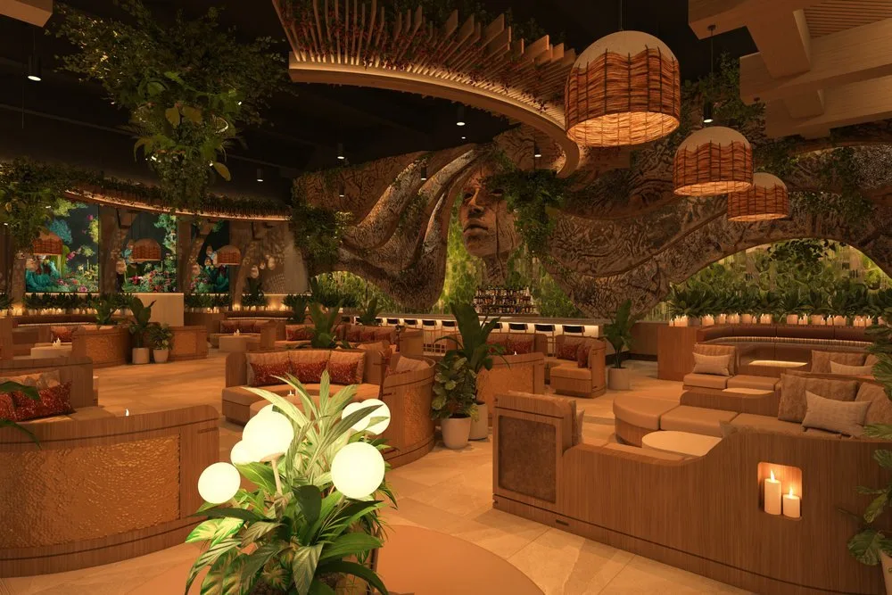 Interior of a cozy, nature-inspired lounge with wooden furniture, lush green plants, and ambient lighting, featuring a large wall art of a woman's face intertwined with tree branches.